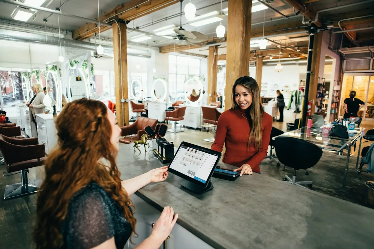 A salon owner checking in a customer at the front desk